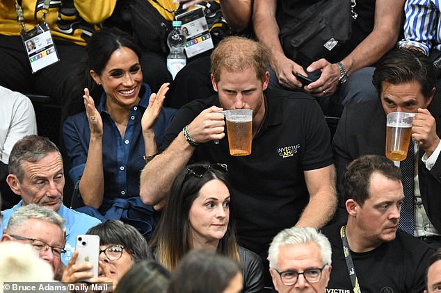 Prince Harry drinking beer while watching the seated volleyball finals at the Invictus Games alongside Meghan Markle