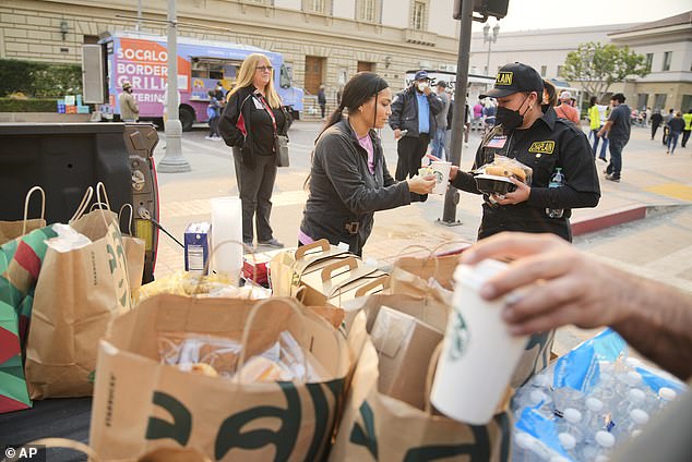 A Starbucks worker delivers coffee to a first responder outside a temporary shelter at the Pasadena Convention Center