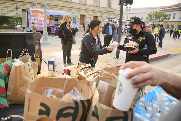 A Starbucks worker delivers coffee to a first responder outside a temporary shelter at the Pasadena Convention Center