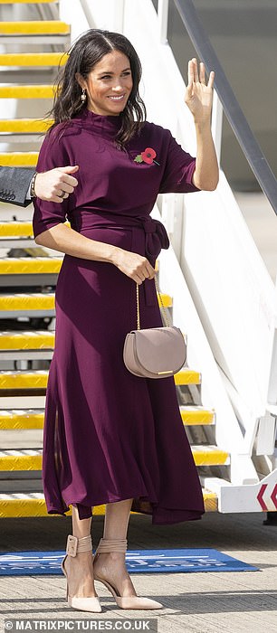 Meghan looked great in this Hugo Boss burgundy        dress as she boarded flight to New Zealand