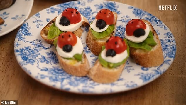 Meghan takes canapes! The Duchess prepares Caprese-style party food as she layers French bread with tomatoes, mozzarella and olives, plus a little basil