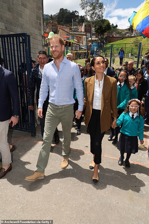 Meghan looked sophisticated in black high-waisted cigarettes pants, which she paired with a white button-up business shirt