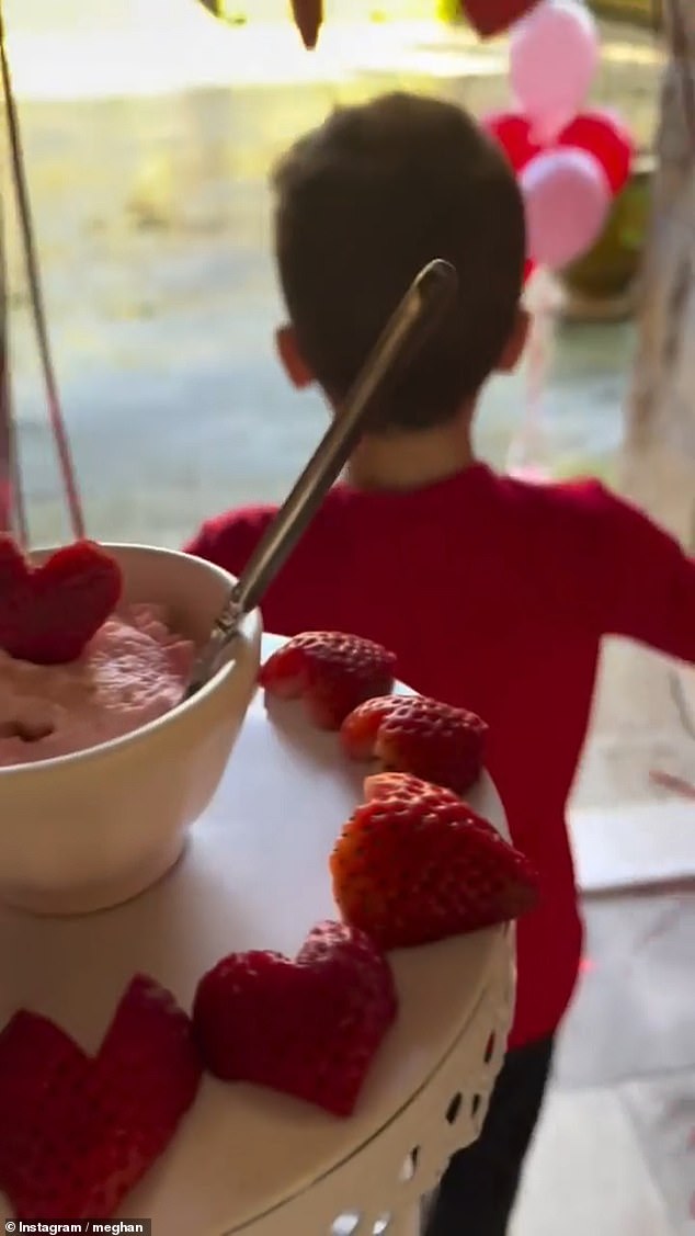 Meghan Markle shared a video (pictured) of herself making a treat for the children, featuring cream cheese bagels and strawberries cut into heart shapes