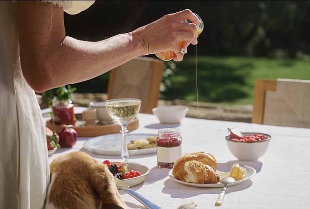 In a photo shared on Instagram, Meghan can be seen drizzling honey over a croissant. Champagne, a jar of jam and a bowl of fruit are also laid out on the table