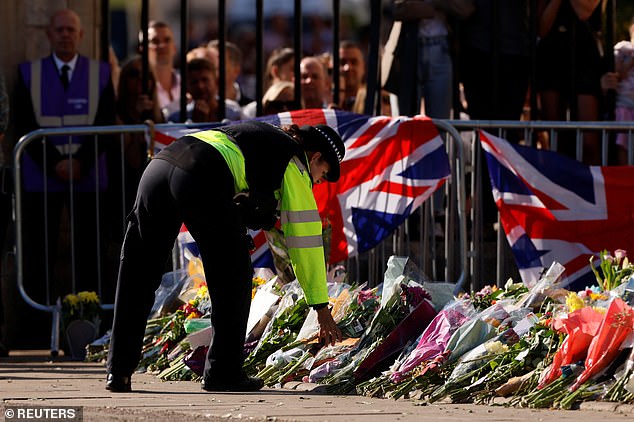 A police officer lays down flowers outside the castle following the passing of Queen Elizabeth II