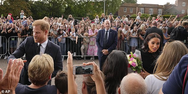 A mindful security guard watches as Duke and Duchess of Sussex meet the mourners