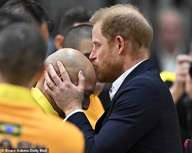 The Duke of Sussex plants a kiss on a bald man's head during the Invictus Games this weekend