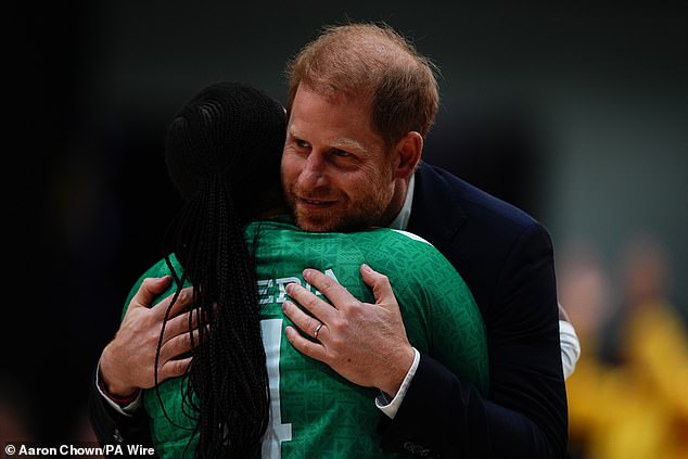 Harry hugs a sportsperson during the medal presentation following the sitting volleyball final on Saturday