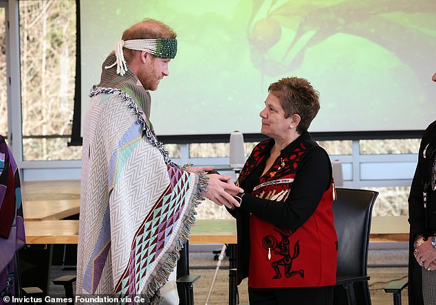 The Prince holds a woman's hands as he wears the First Nation's traditional dress during the eighth day of the Invictus Games