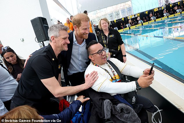 Prince Harry grins as he joins a group selfie at the side of the pool for the Invictus swimming competition