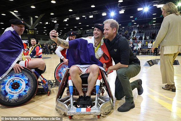 Harry grins as he snaps a selfie with one of the wheelchair rugby stars during the event in Vancouver