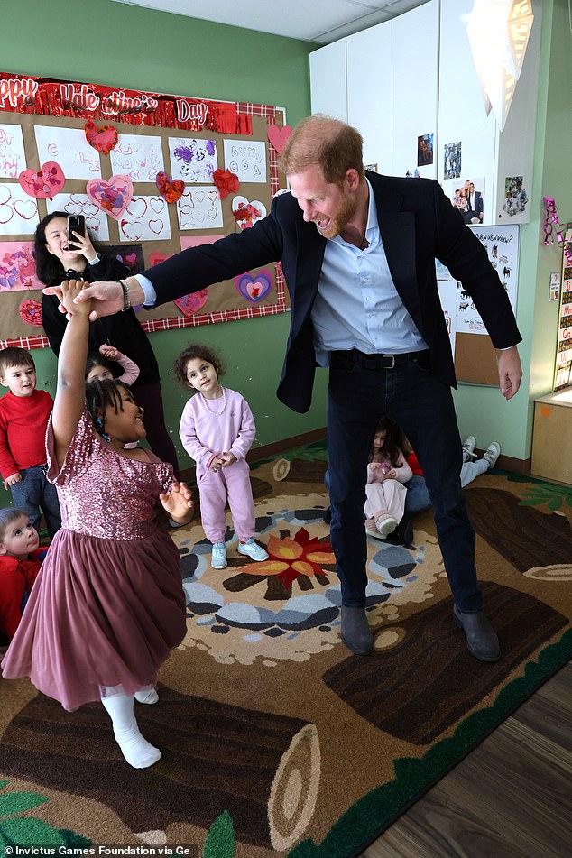 The Duke of Sussex beams as he twirls a little girl in a sparkly outfit while visiting the Tsleil-Waututh First Nation