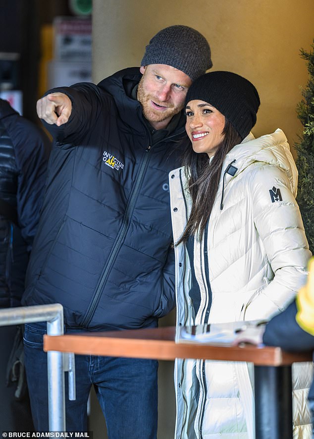 Meghan, the Duchess of Sussex, beams as Prince Harry points towards something in the distance