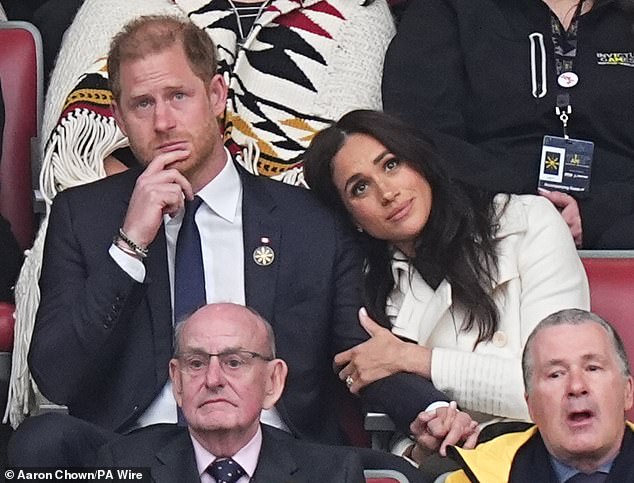 Meghan, 43, dressed in a £2,400 ivory maxi trench coat, rests her head on Harry's shoulder after his speech that watchers believe was a dig at Donald Trump after he criticised his wife