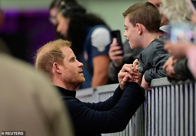 Prince Harry speaks with a ten-year-old boy as he attends the wheelchair basketball yesterday