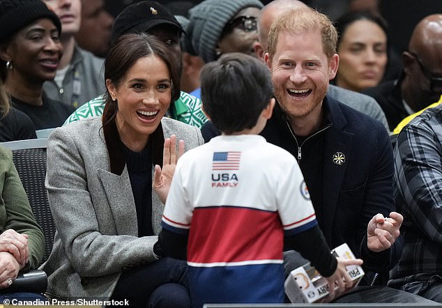 She finished the outfit with a pair of skinny flared jeans from Veronica Beard that costs £200. In this photo, Meghan and Harry are seen greeting a young fan and family member of a Team USA participant