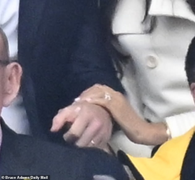 Meghan tentatively placing her hand on Harry's arm during the ceremony with their fingers frequently interlocking; it was 'an emphatic display of bonding', says James