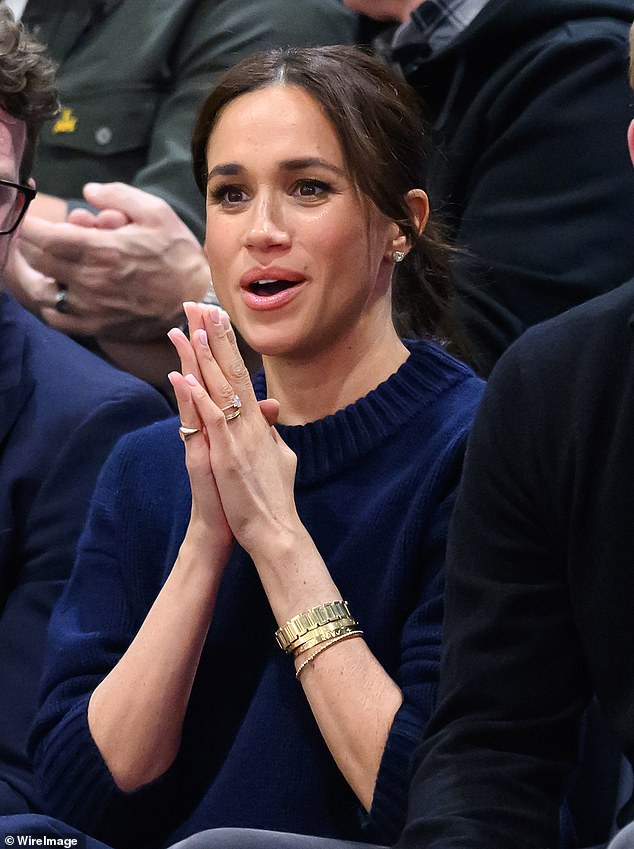 Meghan wears her mother-in-law's gold Cartier tank watch and the signet ring on her right hand at the games in Vancouver, Canada