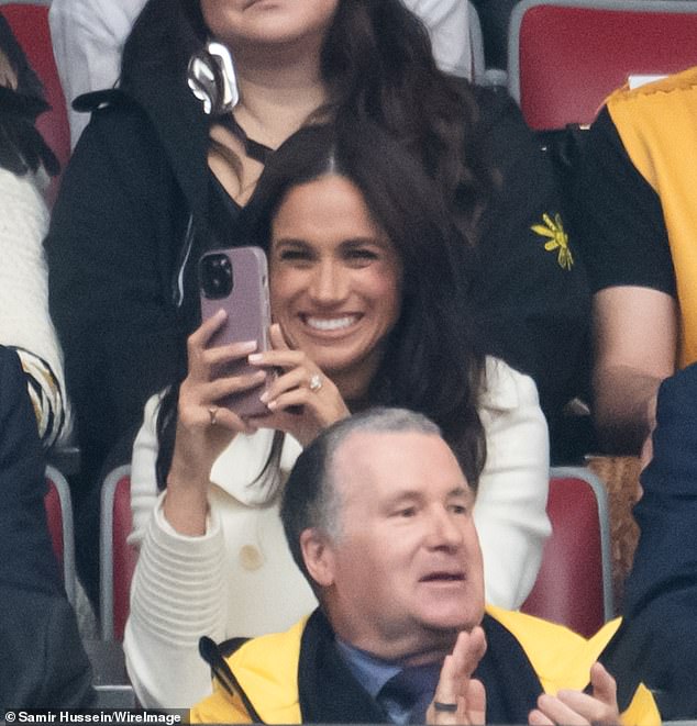 Meghan Markle was spotted in full influencer mode as she filmed close-ups of Prince Harry while the couple watched the Invictus Games opening ceremony in Vancouver, Canada