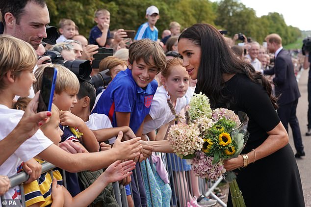 Meghan seemed to want to hold onto flowers during the sombre 40-minute walkabout - despite royal protocol dictating they give them to aides for safety reasons