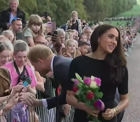 After Meghan dismisses the aide's effort to help, she turns around and smiles - flowers firmly still in hand