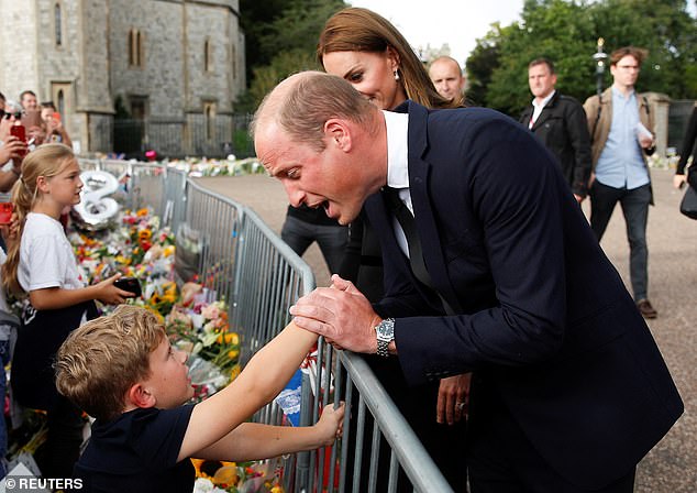 William sweetly grasps the hand of an eager child during the walkabout