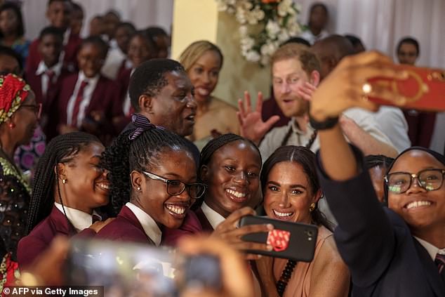 Meghan took a selfie with students as Harry watched at the Wuse Lightway Academy