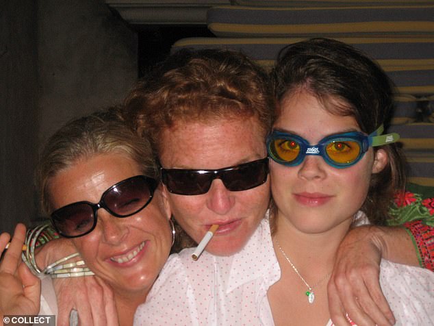 Sarah Ferguson (centre) holds a cigarette in her mouth as she poses with her personal trainer (left) and Princess Eugenie (right) in St Tropez