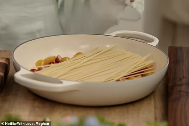 Layering the spaghetti into a Le Creuset dish atop feta and cherry tomatoes before pouring water on top of the dish and cooking it on the stove