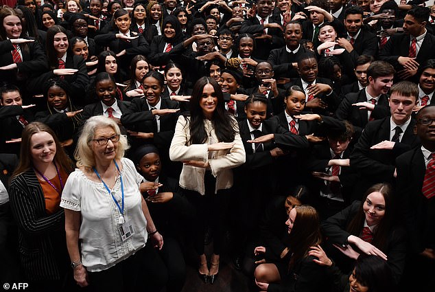 Meghan, Duchess of Sussex poses with school children making the 'Equality' sign following a school assembly during a visit to Robert Clack School in Essex, on March 6, 2020, in support of International Women's Day