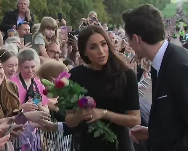 Footage from the notoriously awkward Windsor walkabout has now resurfaced which seems to show Meghan ignoring royal protocol by holding onto flowers and turning away the aide who tried to help her correct the mistake