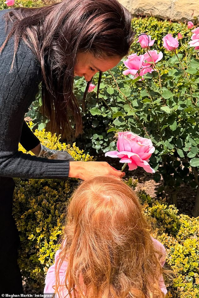 Lilibet's bright red hair is visible in this image shared by Meghan of her children enjoying summer roses in the garden