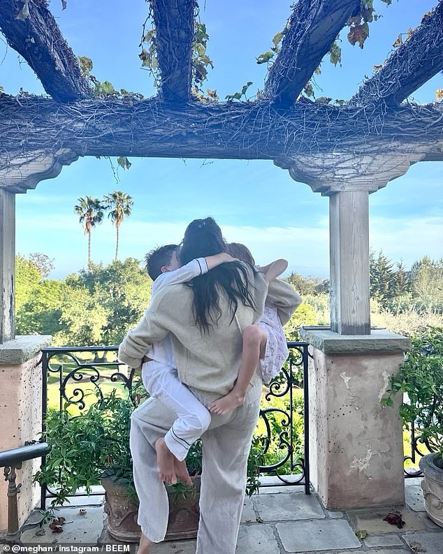 Meghan, pictured at home being climbed on by her children on Mother's Day, is said to be 'distant' and has 'never tried to fit in' in Montecito, a journalist and neighbour has claimed