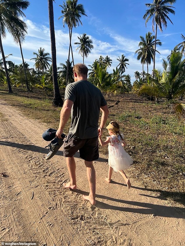 A new photograph of the Duke of Sussex holding Princess Lilibet's hand as they walked along a sandy road barefoot in the sunshine, while he held his shoes and a cap
