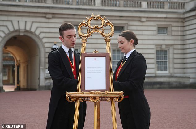 Footmen present the easel in the forecourt of Buckingham Palace to formally announce the birth of Archie
