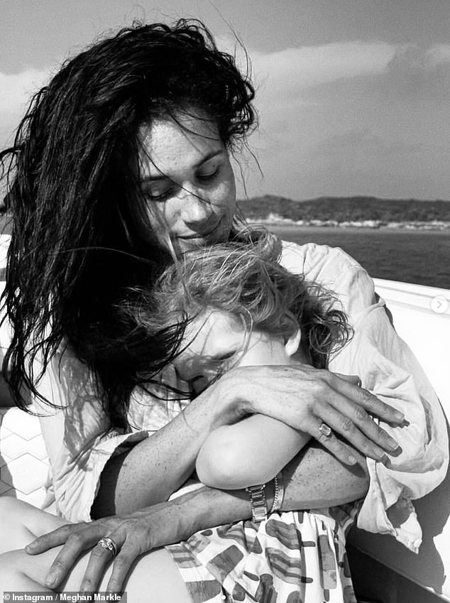 The Duchess of Sussex shared the black and white photo of herself cuddling Princess Lilibet, who was sat on her lap, with the pair both sporting windswept hair