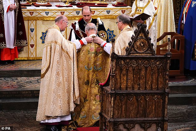 Prince William watches as the Imperial Mantle is placed on Charles's shoulders
